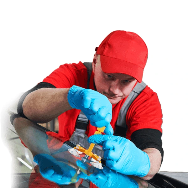 Мужчина в красной кепке ремонтирует лобовое стекло автомобиля